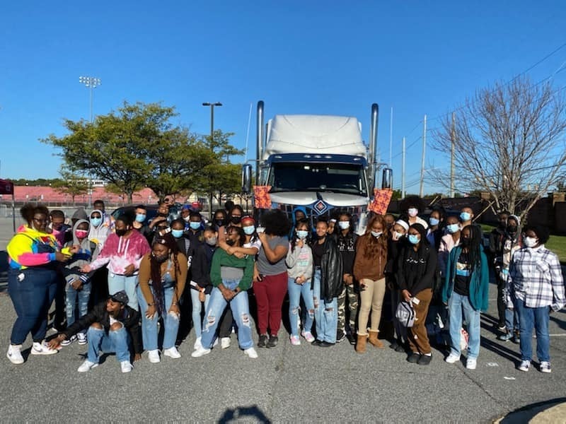 Students standing in front of large truck