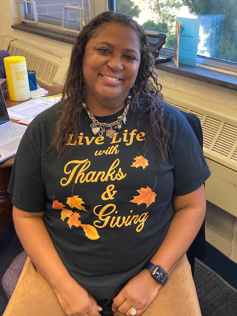 Principal smiles while wearing shirt that reads Live Life with Thanks and Giving